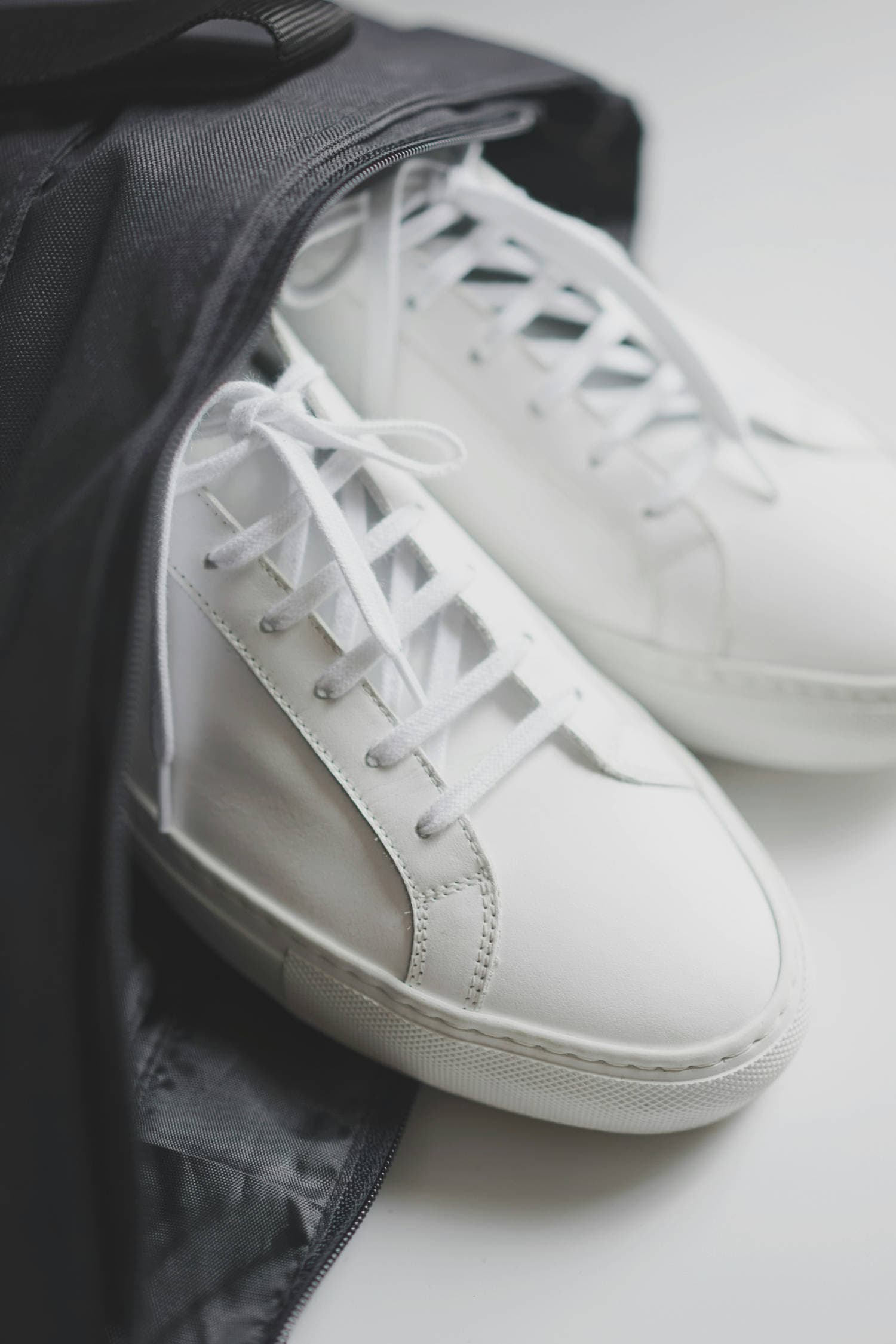 Minimal white sneakers paired with neutral trousers in a minimalist men's wardrobe